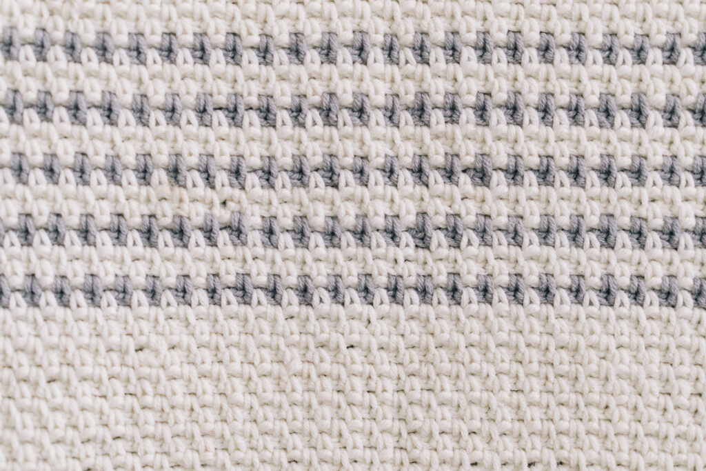 Die Decke ist vollständig im Moosmuster gehäkelt und wechselt zwischen weißen und grau-weißen Streifen. Ich mag den schlichten und minimalistischen Look. Hier geht’s zur kostenlosen Anleitung. #Decke #Streifen #Moosmuster #Häkeln @melaliving